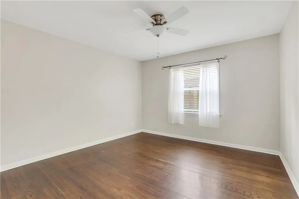 Empty room with ceiling fan, baseboards, and dark wood-style flooring