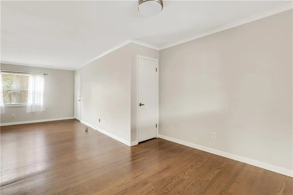Spare room with wood finished floors, baseboards, and crown molding