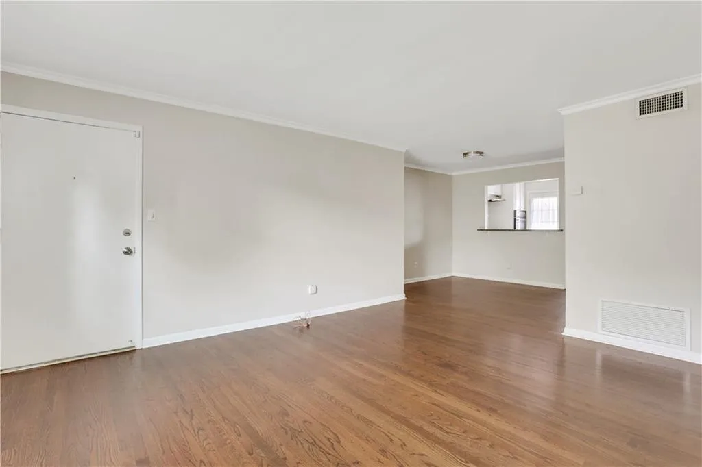 Empty room with wood finished floors, ornamental molding, and baseboards