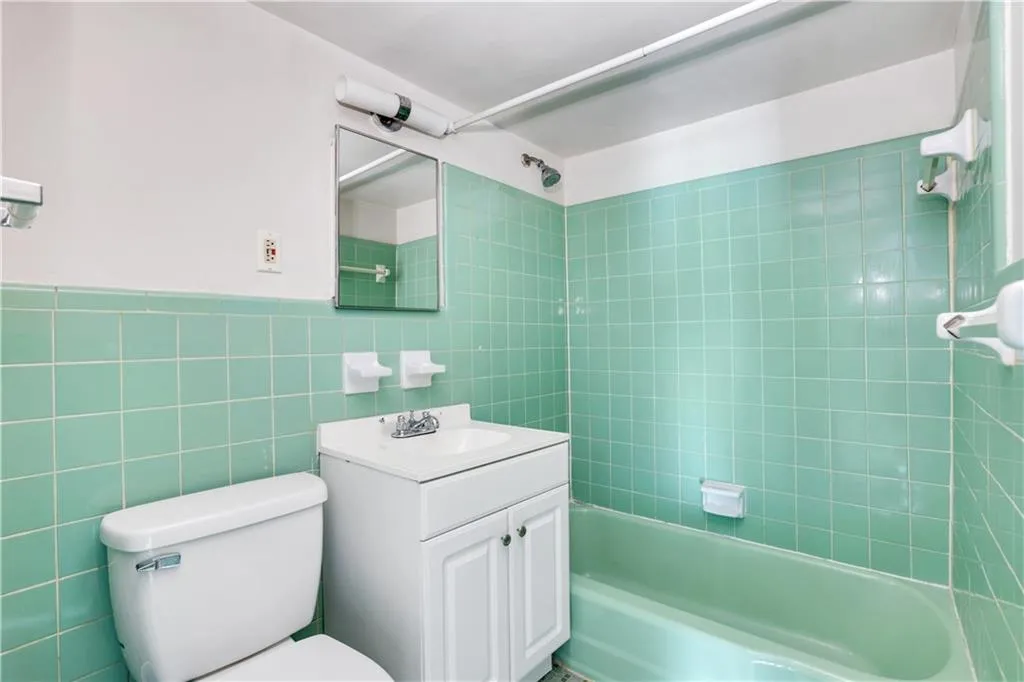 Bathroom with toilet, vanity, tub / shower combination, and tile walls