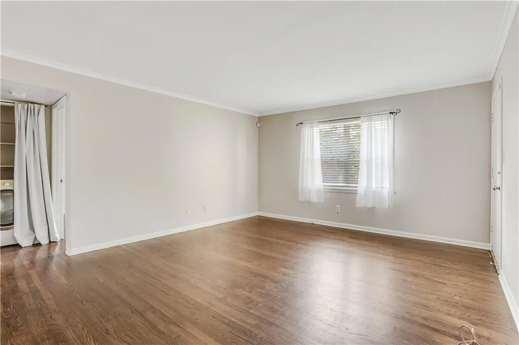 Empty room featuring ornamental molding, wood finished floors, and baseboards