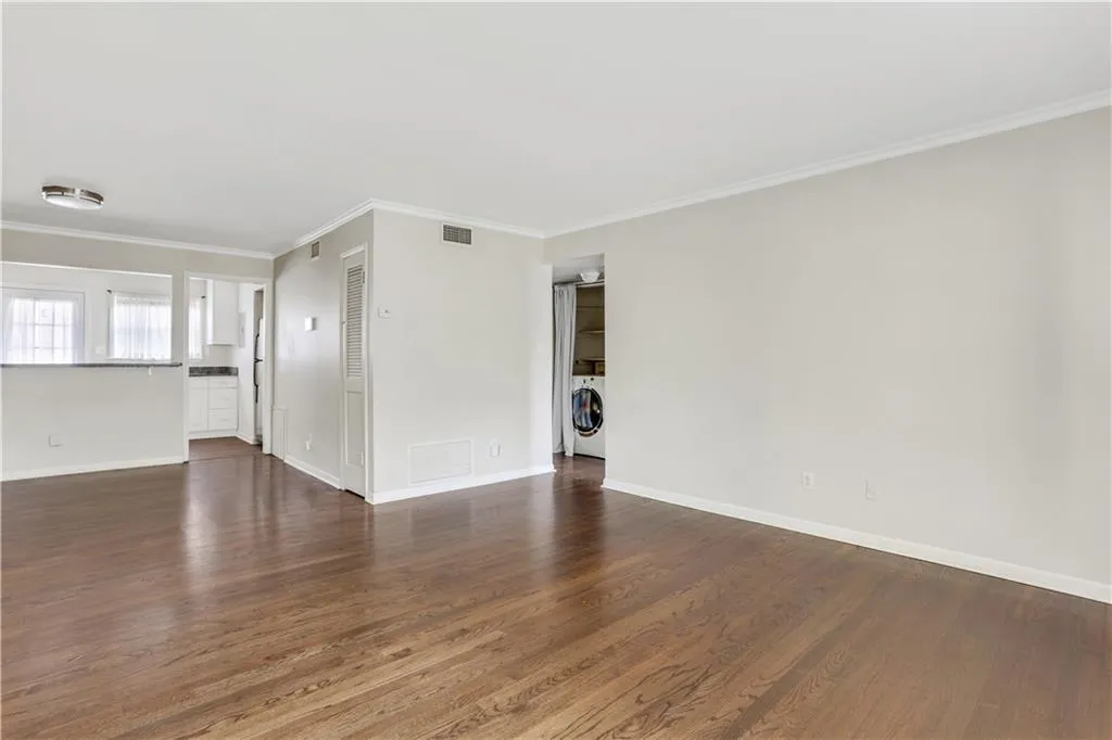 Unfurnished room featuring washer / clothes dryer, dark wood finished floors, crown molding, and baseboards