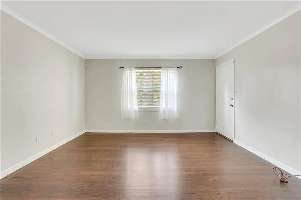 Unfurnished room featuring wood finished floors, baseboards, and ornamental molding