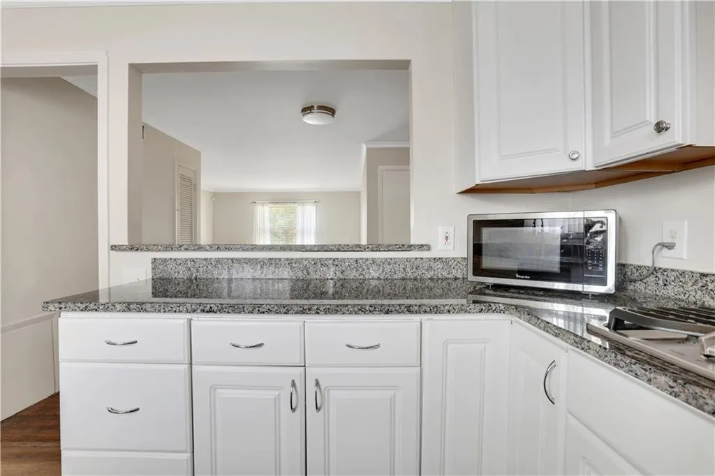 Kitchen featuring stainless steel appliances, white cabinetry, and dark wood-type flooring