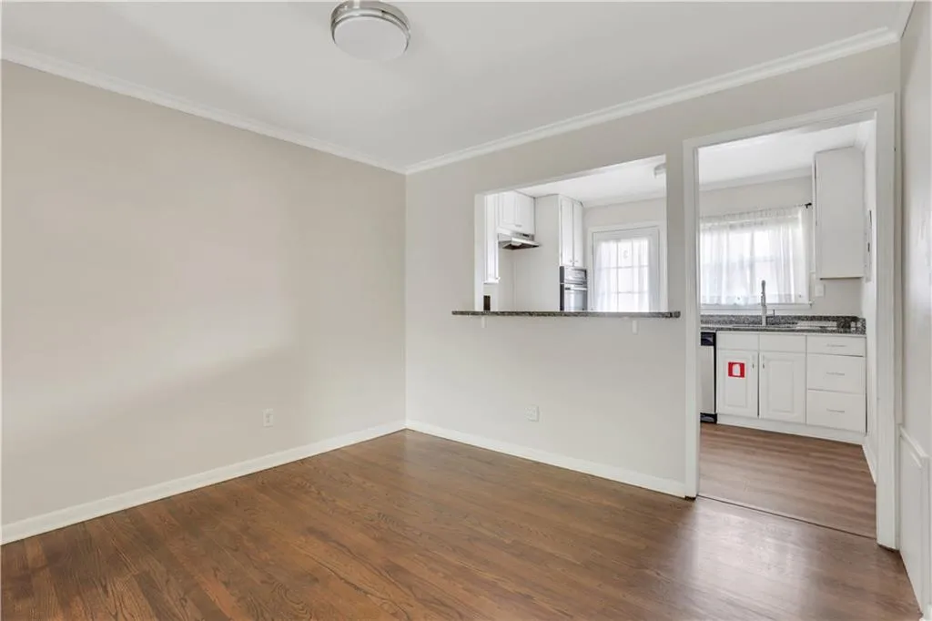 Unfurnished living room featuring ornamental molding, dark wood-type flooring, a sink, and baseboards