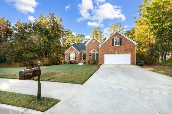 Traditional-style house featuring a front yard, driveway, brick siding, and an attached garage