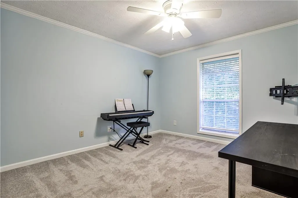 Office featuring crown molding, light colored carpet, a textured ceiling, and ceiling fan