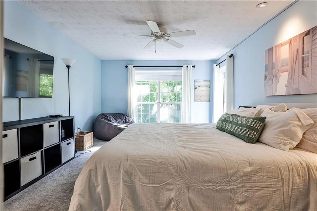 Carpeted bedroom featuring a textured ceiling and a ceiling fan