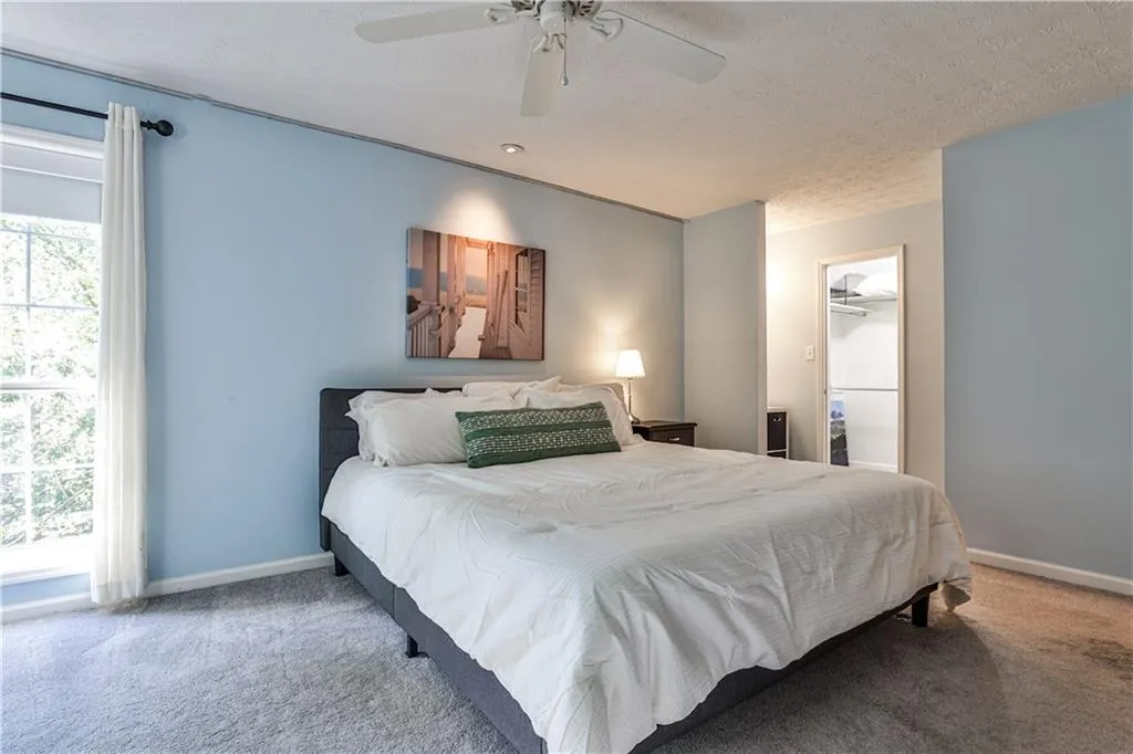Bedroom featuring carpet flooring, a spacious closet, a ceiling fan, and a textured ceiling