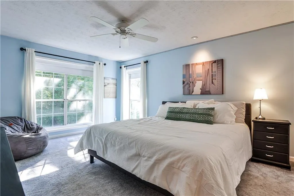 Bedroom featuring a textured ceiling, carpet flooring, and ceiling fan