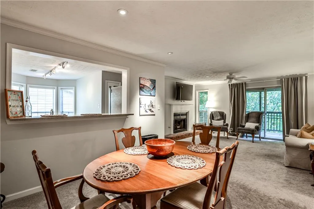 Carpeted dining space featuring a fireplace with raised hearth, a textured ceiling, track lighting, a ceiling fan, and ornamental molding