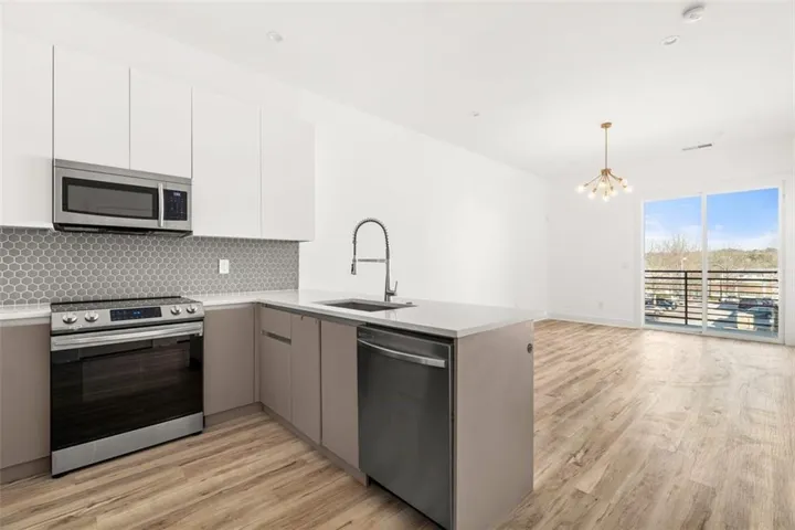Two tone kitchen with stainless steel appliances, two tone cabinetry, modern cabinets, and light wood-type flooring