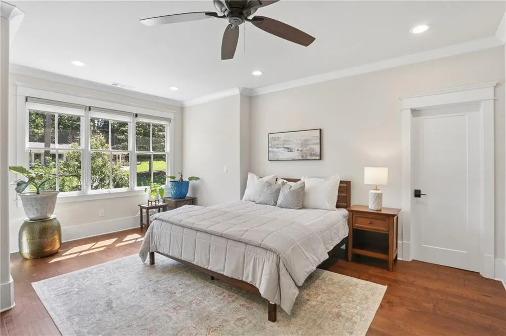 Wood-finish flooring, recessed lighting, crown molding, a ceiling fan, and large windows with integrated blinds