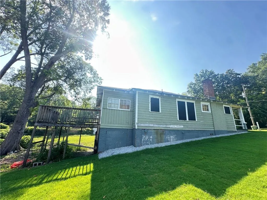 Back of property featuring a yard, a wooden deck, and a chimney