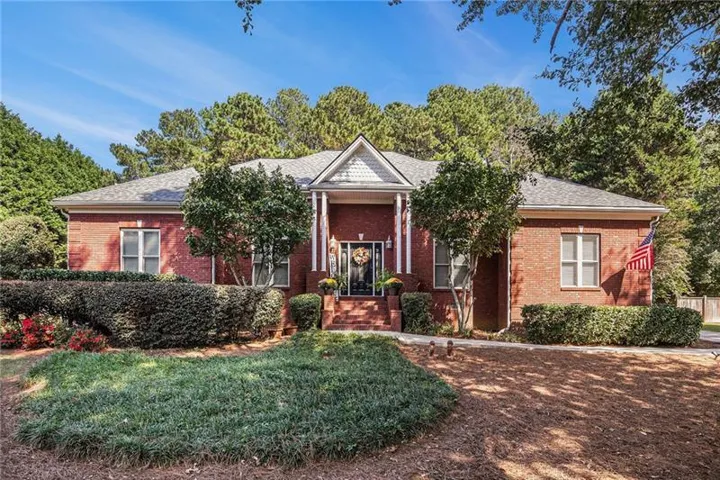 Neoclassical home with brick siding, roof with shingles, and a front yard