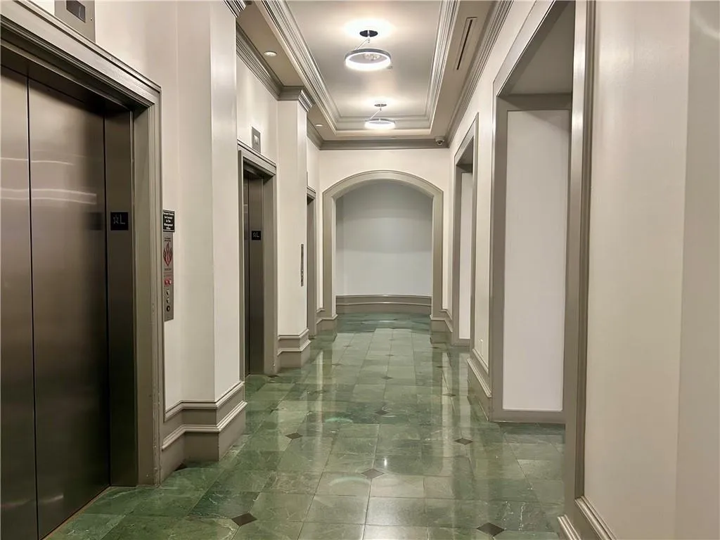 Hallway featuring a raised ceiling, elevator, and crown molding