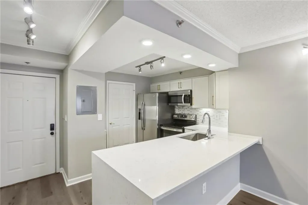 Kitchen featuring white cabinetry, rail lighting, sink, electric panel, and stainless steel appliances