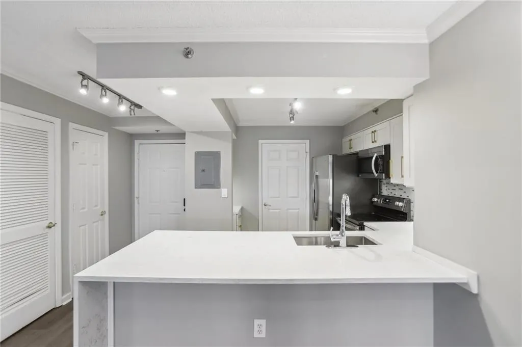 Kitchen with sink, white cabinets, backsplash, kitchen peninsula, and stainless steel appliances