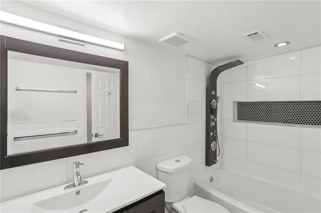 Full bathroom with toilet, tasteful backsplash, tiled shower / bath, tile walls, and vanity