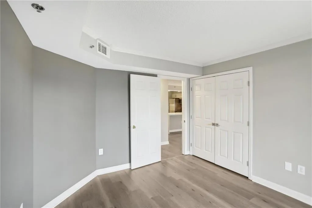 Unfurnished bedroom featuring crown molding, light hardwood / wood-style flooring, and a closet