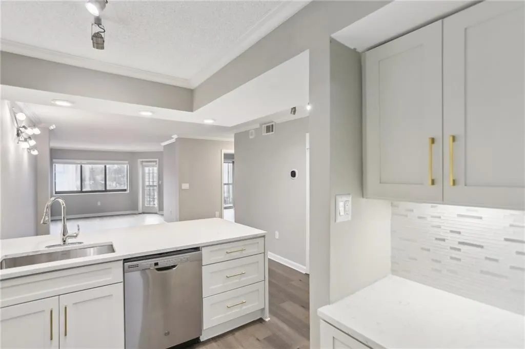 Kitchen with sink, backsplash, white cabinets, and dishwasher