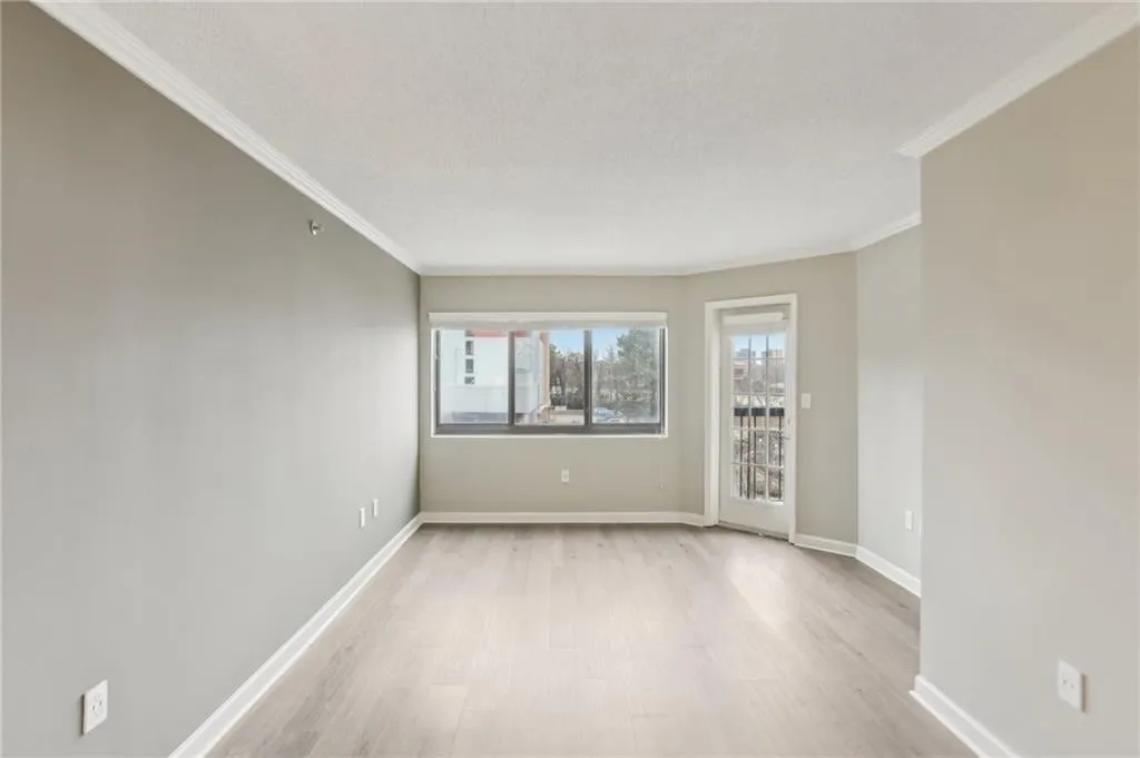 Unfurnished room with light hardwood / wood-style flooring, ornamental molding, and a textured ceiling