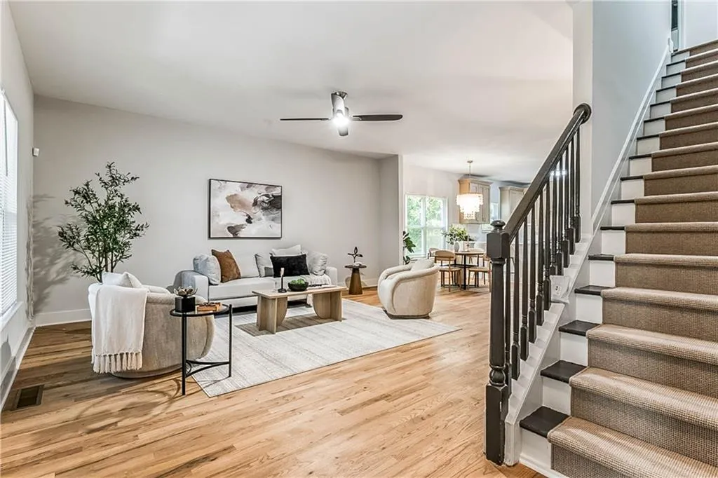 Living room with stairs, light wood-style floors, and ceiling fan