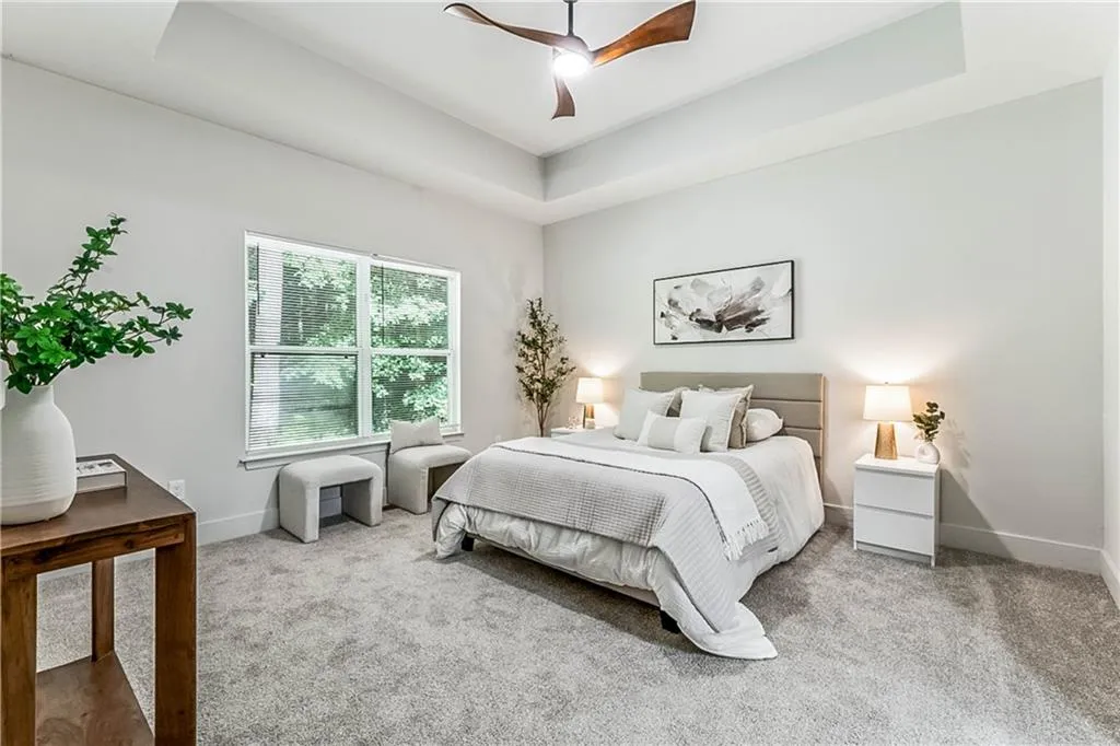 Carpeted bedroom with a tray ceiling and ceiling fan