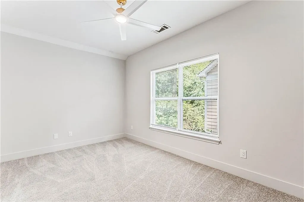 Spare room featuring carpet and ceiling fan