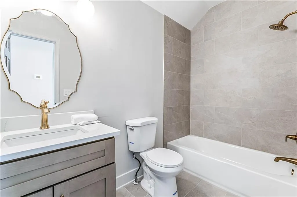 Full bathroom with bathtub / shower combination, vanity, light tile patterned flooring, and lofted ceiling