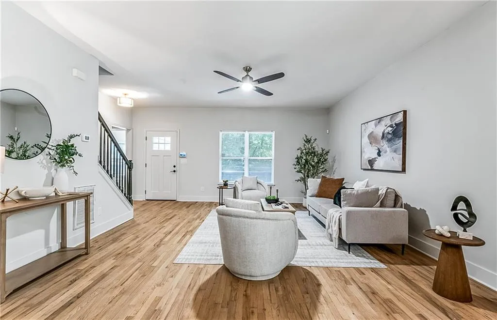 Living area with stairs, light wood-style floors, and a ceiling fan