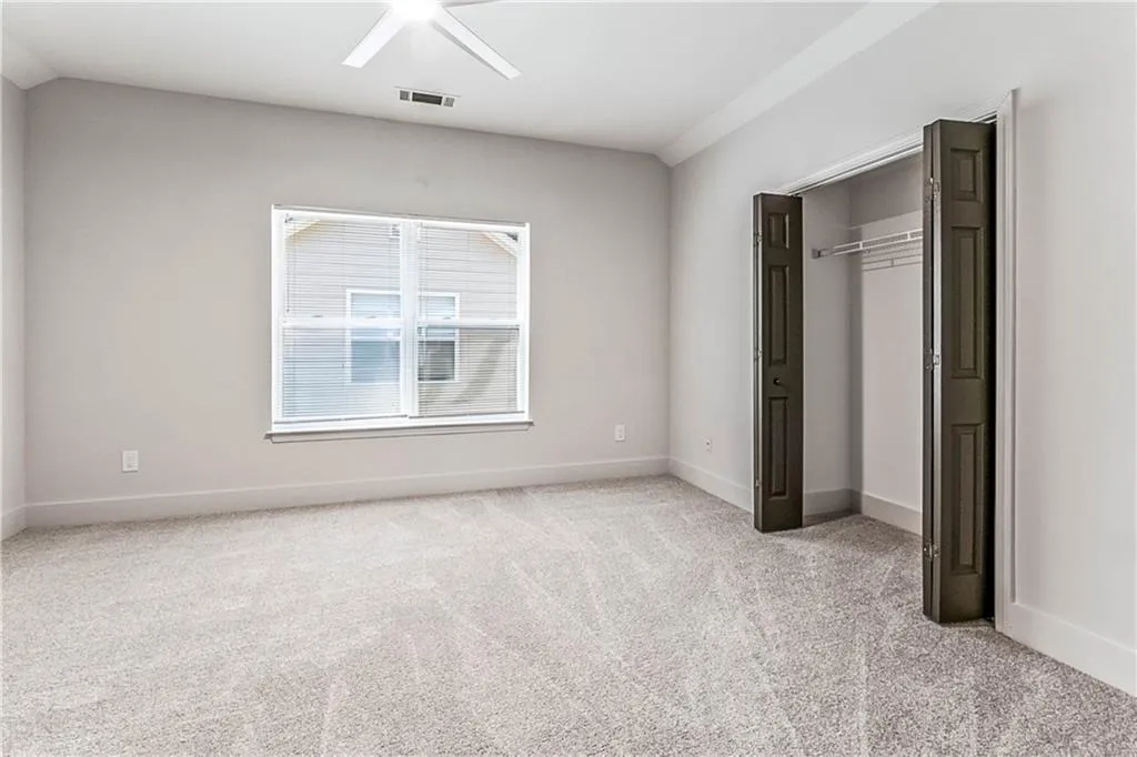 Unfurnished bedroom featuring light colored carpet, a ceiling fan, and a closet