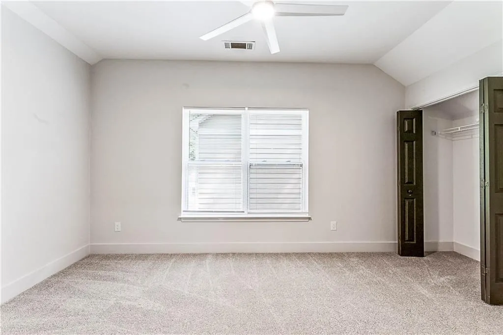 Unfurnished bedroom with light colored carpet, a closet, a ceiling fan, and vaulted ceiling