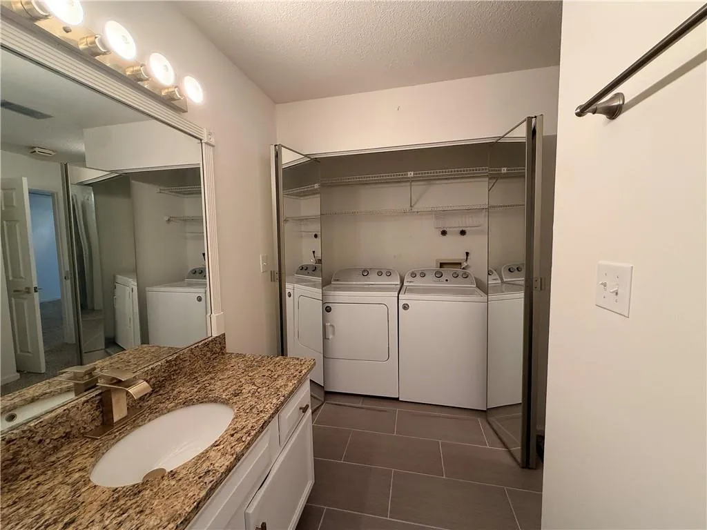 Vanity with a speckled countertop, integrated sink, and white cabinetry