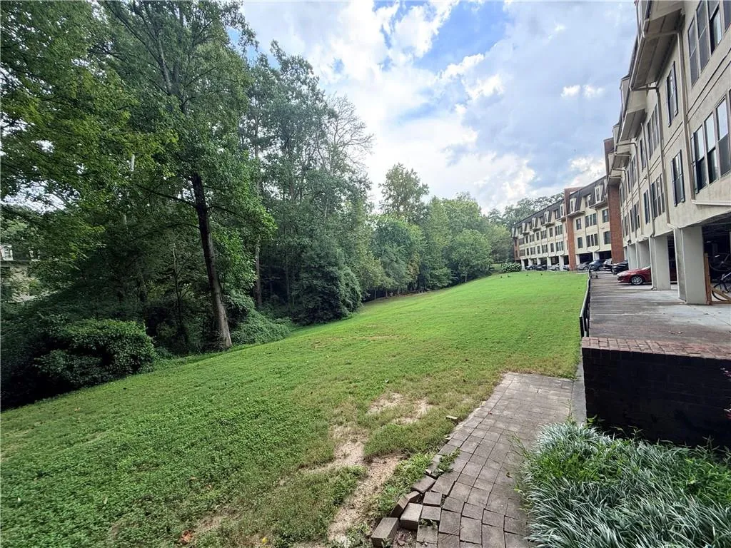 Expansive grassy area bordered by mature trees and residential buildings