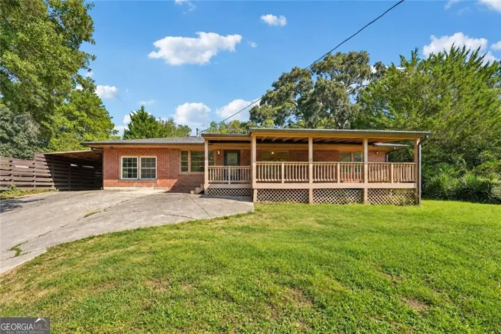 Brick exterior with a covered front porch, wooden deck, and an attached carport