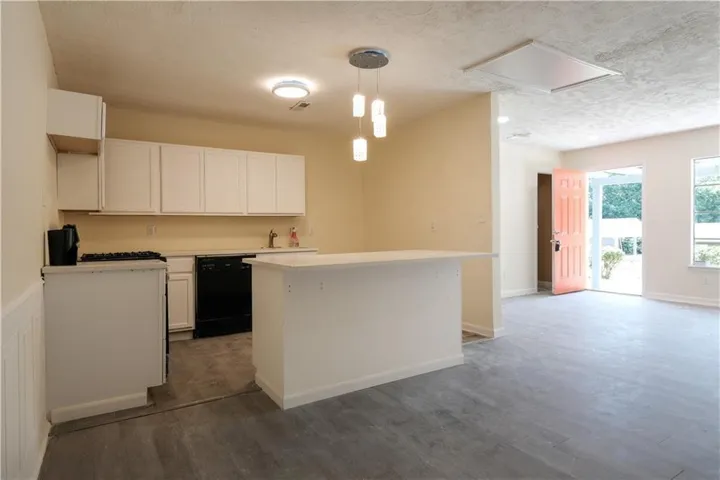 Kitchen with white cabinetry, black appliances, a peninsula island, and wood-finish flooring