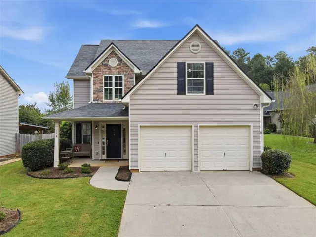 Two-story residence featuring a covered front porch, a two-car garage, and stone facade accents