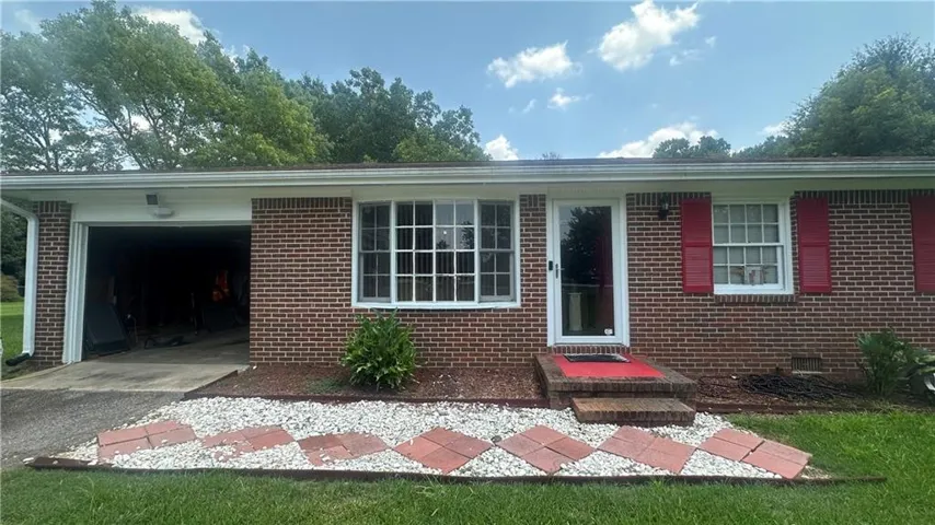 Brick exterior featuring a single-car garage and red decorative shutters