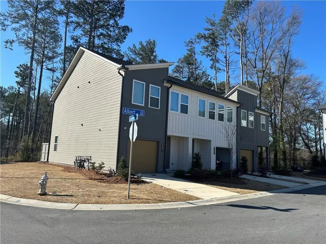 Modern townhome exterior featuring multi-toned siding, a two-car garage, and multiple windows