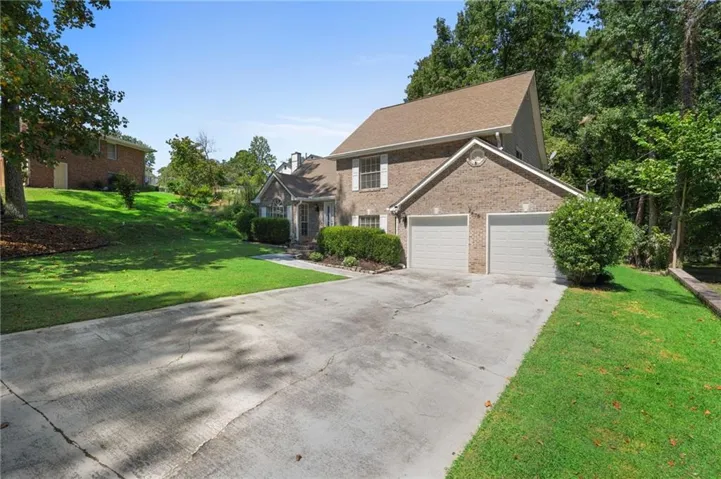 Brick exterior with a peaked roofline, featuring an attached two-car garage with individual doors, and a concrete driveway