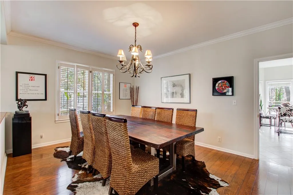 Dining area featuring wood-type flooring, ornamental molding, and a chandelier
