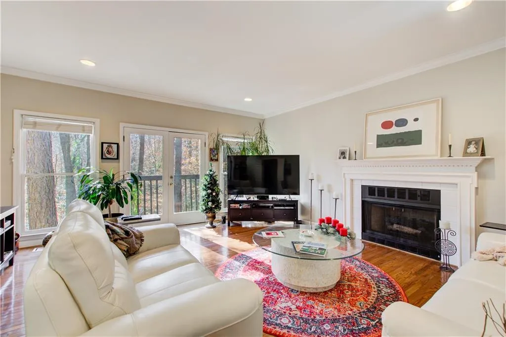 Living area featuring ornamental molding, a fireplace, wood finished floors, recessed lighting, and french doors