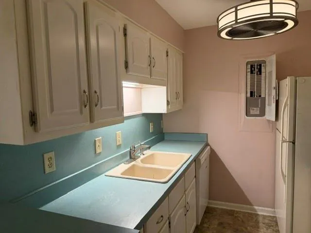 White cabinetry, dual-basin sink, light-colored countertops, and overhead lighting fixture