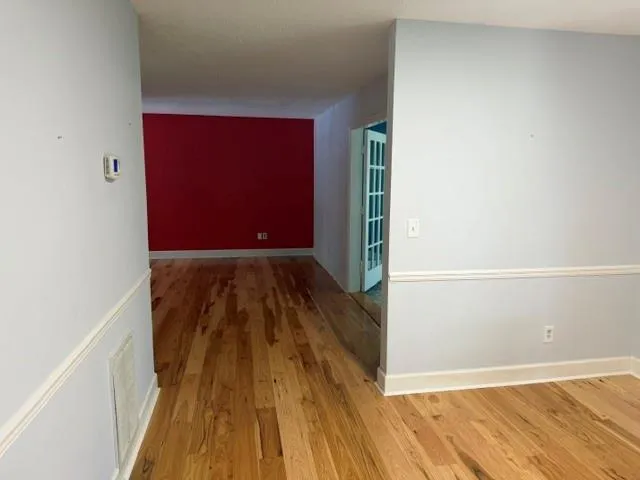 Hardwood flooring throughout, neutral painted walls with white trim, and a prominent red accent wall
