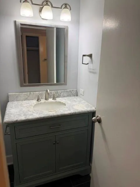 Vanity with a light gray cabinet, white countertop, and an undermount sink, complemented by a brushed nickel faucet