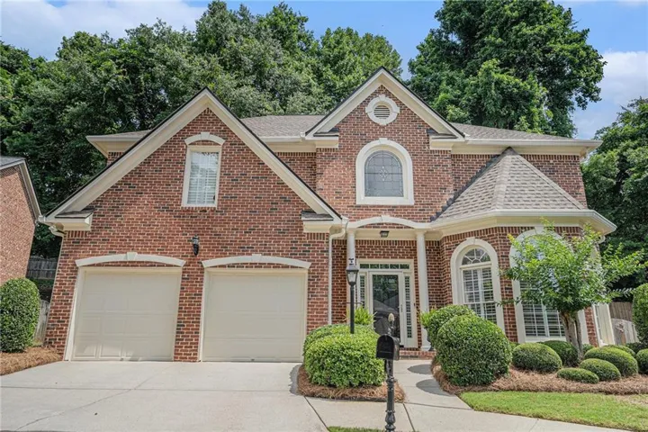 View of front facade with brick siding, driveway, a shingled roof, and an attached garage