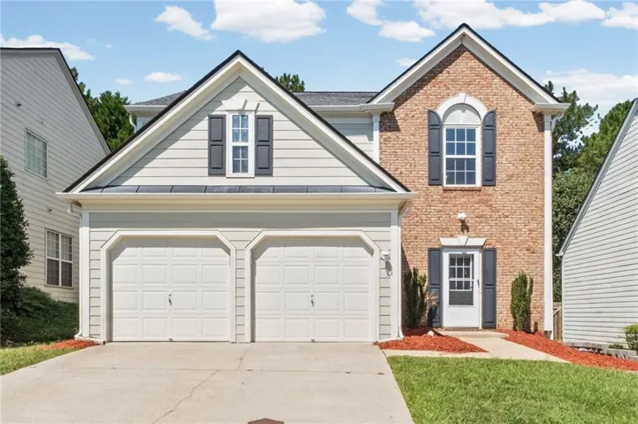 Front facade featuring brick and siding, a two-car garage, and a concrete driveway