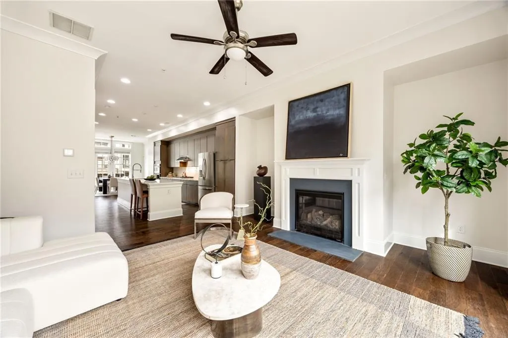 Living area with dark wood-type flooring, a glass covered fireplace, visible vents, and recessed lighting