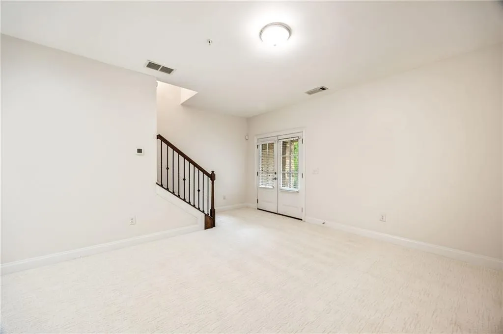Spare room with light carpet, baseboards, stairs, and visible vents